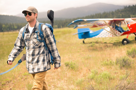 Man walking away form monoplane in wilderness