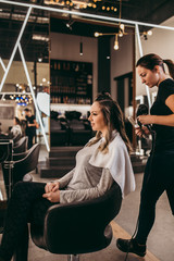 Beautiful brunette woman with long hair at the beauty salon getting a hair blowing. Hair salon styling concept.