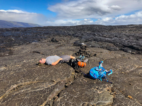 Backpacker resting in volcanic landscape, Puna Coast Trail, Hawaii Volcanoes National Park, Hawaii Islands, USA