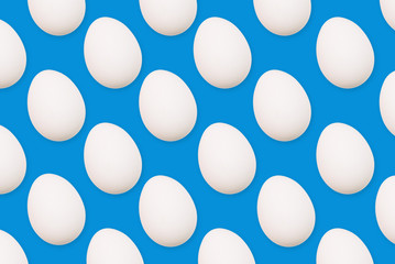 White eggs on a blue background. Many eggs arranged in a row. View from above
