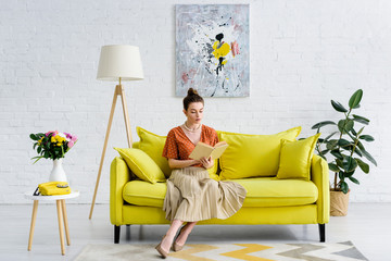elegant woman sitting in living room and reading book