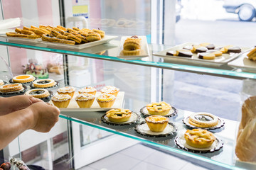hands are putting tidy rice puddings in a showcase of a sweet shop