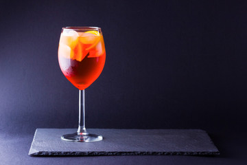 Cocktail aperol spritz on dark background. Summer alcohol cocktail with orange fruit in minimalism...