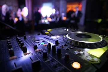 Fototapeta na wymiar DJ console mixer at a nightclub. The disco, Banquet, people blurred background dancing. 