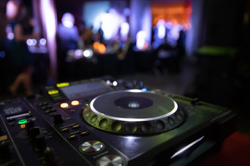 Obraz na płótnie Canvas DJ console mixer at a nightclub. The disco, Banquet, people blurred background dancing. 