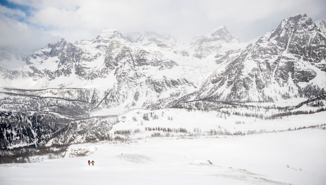Two alpinists climb on a slope above the Valley of Devero in a stormy day with Cervandone group in background. Baceno, Piemonte, Italy.
