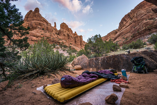 Sleeping pad and sleeping bag on ground sheet in desert canyon.