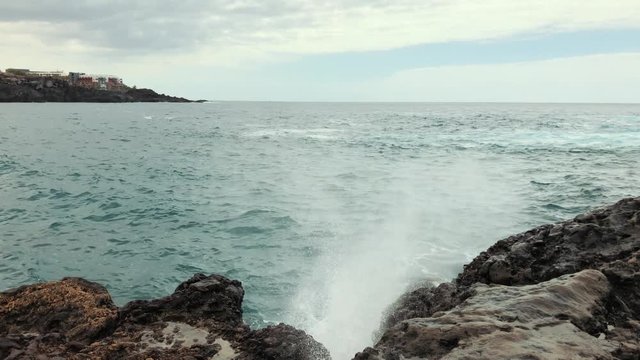 A sea wave runs over a sandy beach. A picturesque shore of stones and trees 4k