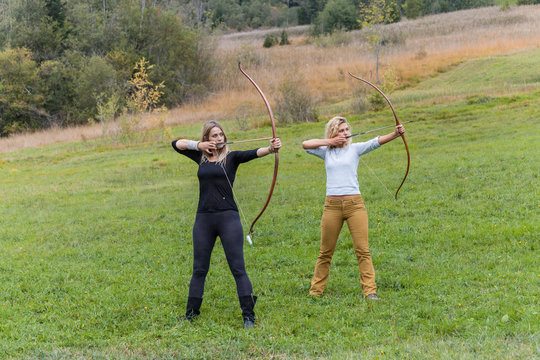 Two archer standing on a meadow aiming with her bows