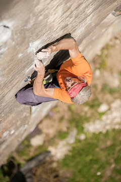 Man climbing Re Azul, an historic 7b route on granite crag of Balmanolesca, Varzo, Italy.
