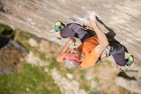 Man climbing Re Azul, an historic 7b route on granite crag of Balmanolesca, Varzo, Italy.
