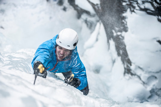 Man lead climbing an ice fall in the middle of a snow storm  in Simplon Pass, Valais, Switzerland.