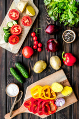 cooking with raw vegetables on dark wooden background top view