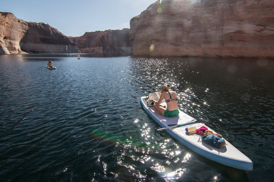 Woman looking at map while sitting on paddleboard, Lake Powell, Utah, USA