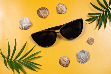 Flat lay na żółtym tle, okulary przeciwsłoneczne i muszelki. Inspiracja na wakacje, lato, czas wolny © Nicoletta