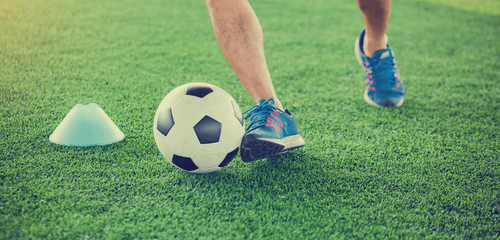 Fototapeta premium soccer player put blue sport shoes to jogging with trap and control football between cone markers