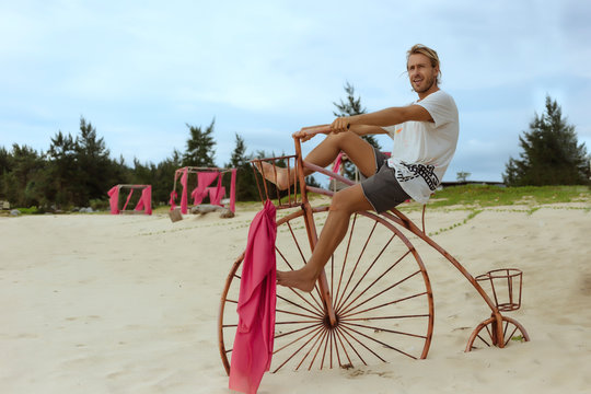 Man sitting on high wheel bicycle on beach