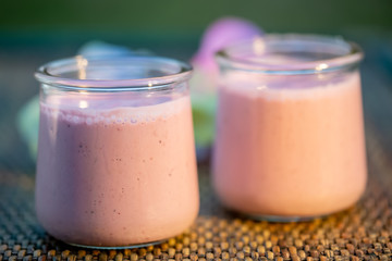 Blueberry yogurt in glass jars on rustic table in summertime. Homemade milk sweet yogurt with bilberry. Dessert. Evening light. Soft focus. Blurry background. Close-up. Macro.