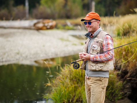 Side view of man with fishing rod standing by river