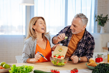 Couple of businessmen feeling joyful while cooking together