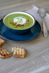 Creamy vegetable soup with kale, cabbage, celery and millet, decorated with olive oil, yoghurt sauce and chilli flakes. Served with toasted bread and lemony yoghurt sauce. Selective focus.