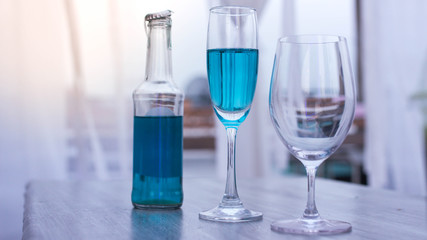 Wine Glasses and Blue Wine with Glasses of Champagne on table at restaurant Over sun background.