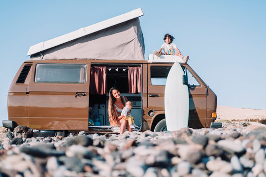 Mother with children by vintage camper van on stony beach