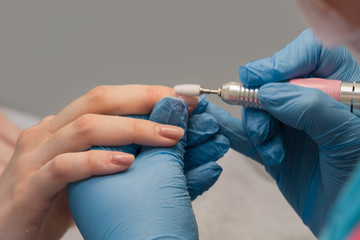 The manicurist processes old gel varnish a mill