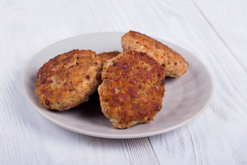 cutlets on a grey plate, on a white wooden background