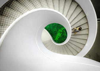 Woman walking up spiral staircase decorated with checked pattern