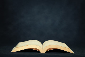 Open old book on dark background