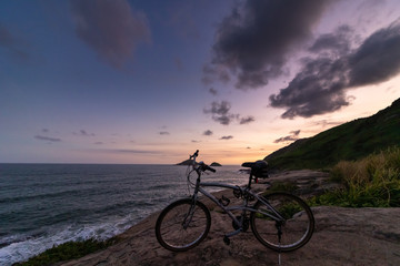 Fototapeta na wymiar bicycle with the background a multicolored sunset at the lookout for beach in rio de janeiro brazil