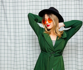 Young style woman in sunglasses and green cloak in 90s style