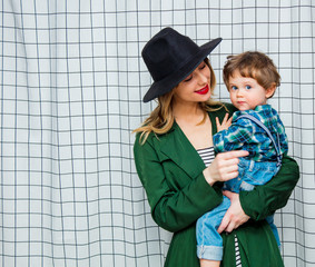 woman in hat and green cloak in 90s style with toddler boy