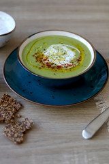 Creamy vegetable soup with kale, cabbage, celery and millet, decorated with olive oil, yoghurt sauce and chilli flakes. Served with seed crackers and lemony yoghurt sauce. Selective focus.