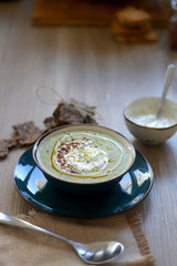 Creamy vegetable soup with kale, cabbage, celery and millet, decorated with olive oil, yoghurt sauce and chilli flakes. Served with seed crackers and lemony yoghurt sauce. Selective focus.