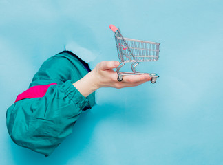 Female hand in 90s style jacket holding supermarket cart