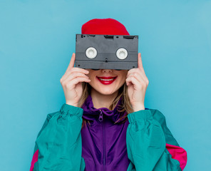 woman in red hat, sunglasses and suit of 90s with VHS cassette