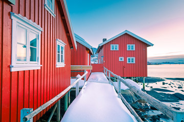 Classic red rorbu - traditional  Norwegian wooden fishing house at the shore of ocean. Location -...