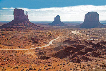 Fototapeta na wymiar A long lonely road leads to the towers of Monument Valley.