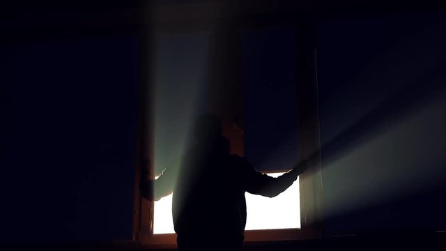 In dark shot of silhouette man open striped blinds on a window i dirty window jalousie installing apartment interior inside sunshine light view closeup flat slow motion