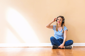 Young woman with headphones against a big interior wall