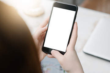 close-up on hand holding phone showing white screen on desk at coffee shop.