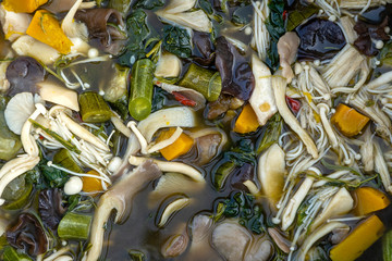 Fototapeta na wymiar Mushroom soup boiled in big pot, Thai style food. Street food in local market, Thailand, closeup