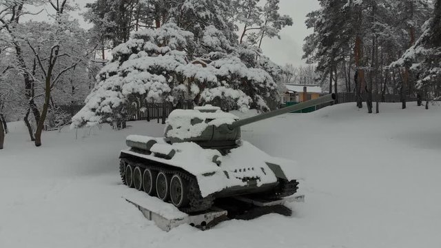 Tank T-34 historical monument. 4K, view of the monument to the tank T-34, installed in the city park among the snow-covered conifers