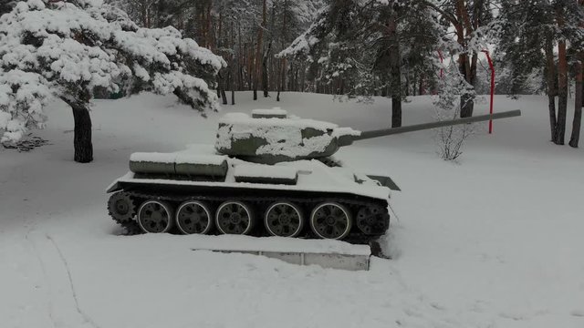Tank T-34 historical monument. 4K, view of the monument to the tank T-34, installed in the city park among the snow-covered conifers