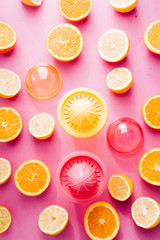 Fototapeta na wymiar Orange and lemon juice maker, fresh summer juice, cut lemon and orange fruit with red and yellow juice container and squeezer,top view, on a pink board with strong backlight