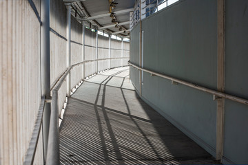 Walkway with high fence with hand rail runs along the wall.