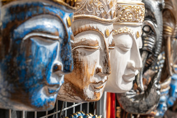 Wooden mask with the image of the Buddha on display for sale on street market in Bali, Indonesia. Handicrafts and souvenir shop display, close up