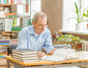 Senior man reading a book in the library